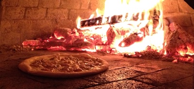 12" pizza cooking in a wood fired oven
