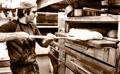 chef removing fresh loaves of ciabatta from the oven
